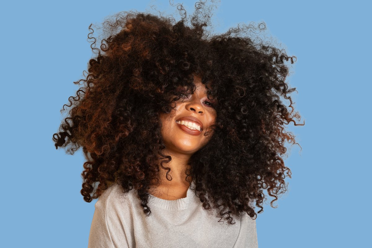 The same subject cut out and composited onto a new blue studio background, with the intricate curls preserved.